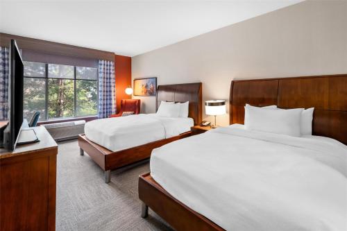 a hotel room with two beds and a television at Hilton Garden Inn Overland Park in Overland Park