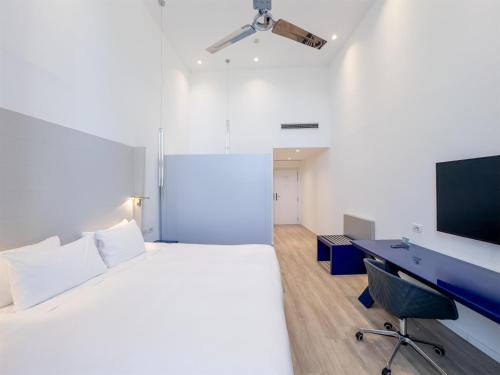 a bedroom with a bed and a desk and a tv at Hilton Sorrento Palace in Sorrento