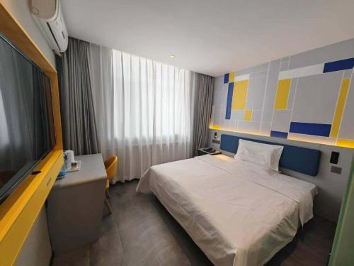 a bedroom with a bed and a desk and a television at 7 Days Inn Hohhot Hailiang Xinhua Square Metro Station in Hohhot