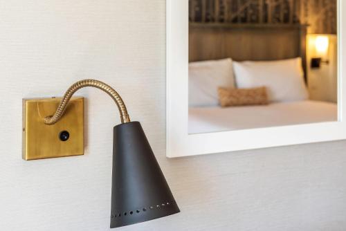 a black lamp hanging on a wall next to a mirror at UpValley Inn & Hot Springs, an Ascend Collection Hotel in Calistoga