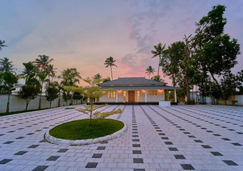 a house with a tree in the middle of a courtyard at Ashtamudi Luxe Villa by VOYE HOMES in Kollam