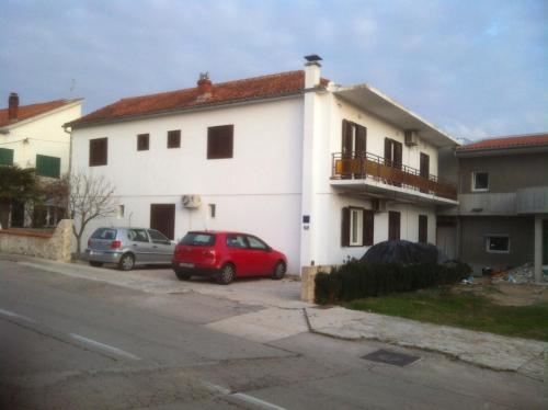 a white house with two cars parked in front of it at Rooms Ivica Vodice in Vodice