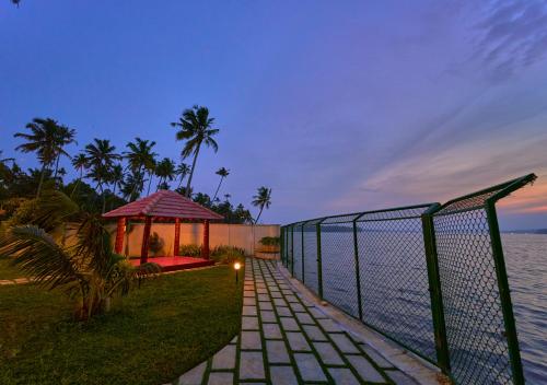 a fence next to the water with a gazebo at Ashtamudi Luxe Villa by VOYE HOMES in Kollam