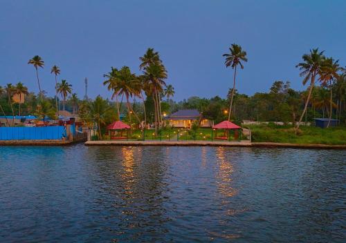 a body of water with palm trees and a resort at Ashtamudi Luxe Villa by VOYE HOMES in Kollam