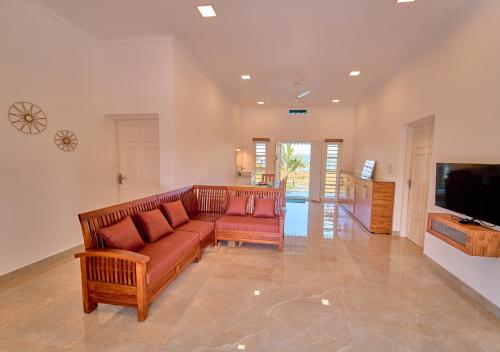 a living room with a couch and a flat screen tv at Ashtamudi Luxe Villa by VOYE HOMES in Kollam