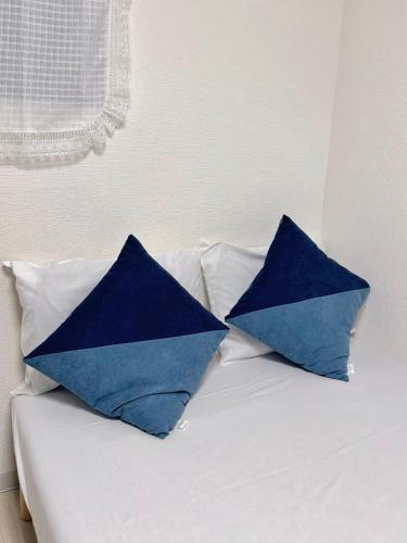 two blue pillows sitting on top of a bed at アークス練馬 in Tokyo