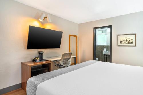 a hotel room with a bed and a desk with a television at La Luna Inn, an Ascend Collection Hotel in San Francisco