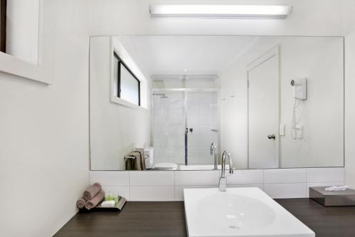 a white bathroom with a sink and a shower at Elm Tree Motel in Warrnambool
