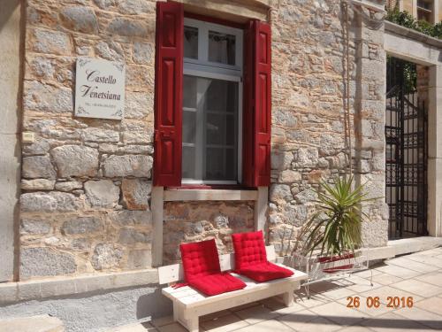 two red pillows sitting on a bench in front of a window at Castello Venetsiana in Symi