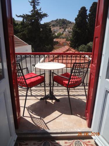 a patio with a table and chairs on a balcony at Castello Venetsiana in Symi