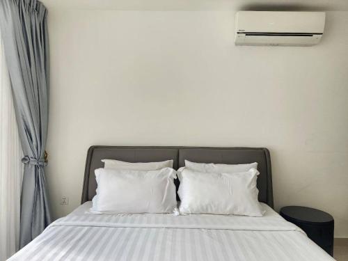 a bed with white sheets and pillows in a room at The PeAk Residence, Multi-Apartment by Emma in Phnom Penh
