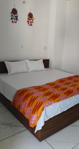 a bed with an orange and white blanket on it at The Stay, Rishikesh in Birbhaddar