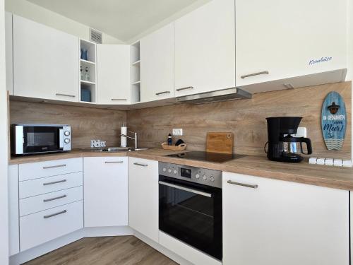 a white kitchen with white cabinets and a microwave at Vier Jahreszeiten "Strandglück" im Haus 2 Wohnung 45 in Großenbrode-Kai