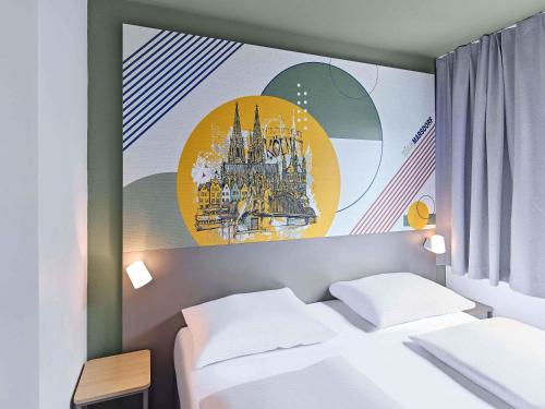 a room with a bed and a painting on the wall at B&B HOTEL Köln-Marsdorf in Cologne