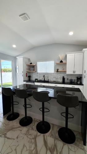 a kitchen with black bar stools and white cabinets at NEW PHX Pool Home With Deep End and Central Location in Phoenix