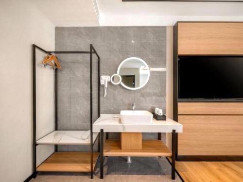 a bathroom with a sink and a mirror and a tv at GreenTree Inn Harbin Central Avenue in Harbin