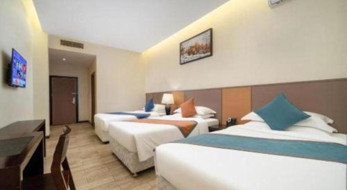 a hotel room with three beds and a desk at Zhuhai Aqueen Hotel in Zhuhai