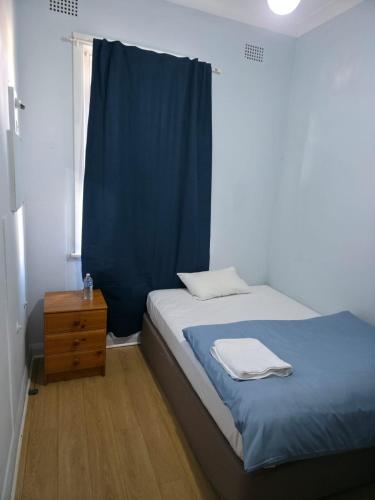 a bedroom with a bed with a blue curtain and a dresser at Court House Hotel in Lithgow