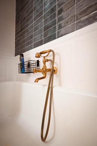 a bathroom with a gold faucet and a bath tub at Sibla Residence, Unique Experience Heritage House in Lugoj