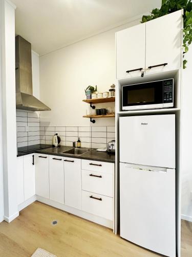 a kitchen with a white refrigerator and a microwave at Skytower views, Wi-Fi, washer & dryer!! in Auckland