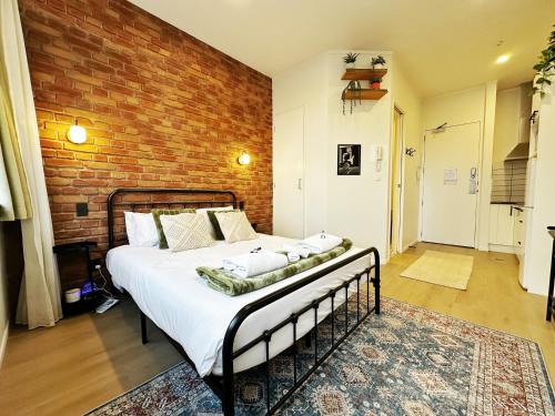 a bedroom with a large bed with a brick wall at Skytower views, Wi-Fi, washer & dryer!! in Auckland