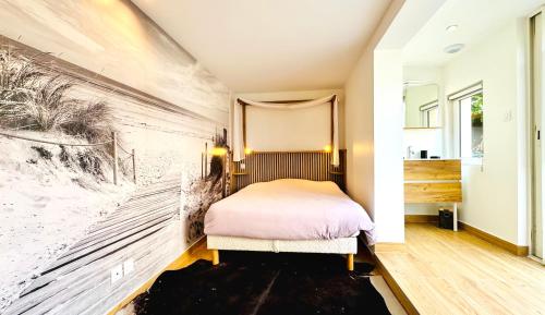 ein Schlafzimmer mit einem Bett und einem Gemälde an der Wand in der Unterkunft Maison de vacances à 900m de la plage in Stella-Plage