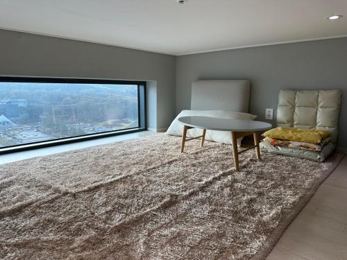 a living room with a table and a chair and a large window at Buldang Hot Place in Ch'ŏnan-yŏk