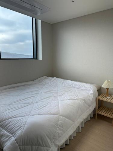 a white bed in a room with a window at Buldang Hot Place in Ch'ŏnan-yŏk