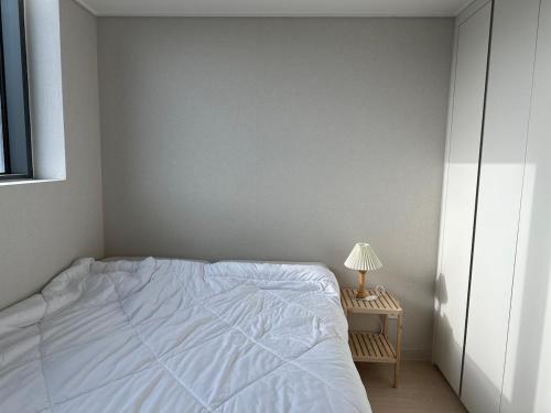 a bedroom with a white bed and a table with a lamp at Buldang Hot Place in Ch'ŏnan-yŏk