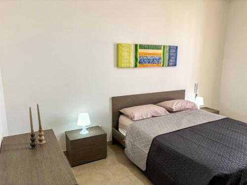 Un dormitorio con una cama y una mesa con una lámpara. en Sofia Kite Apartment, en Marsala
