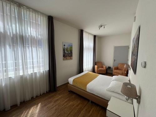 a hotel room with a bed and a chair and window at Hotel Residence Le Coin in Amsterdam