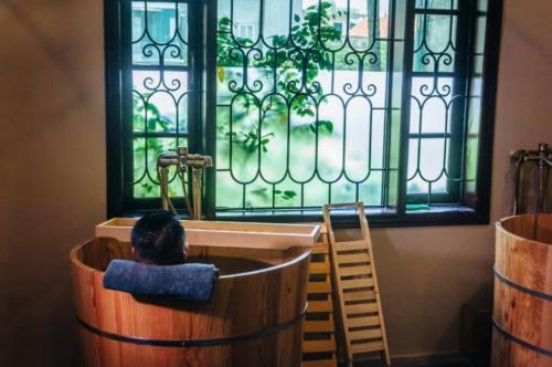 a person sitting in a barrel looking at a window at Ngải Spa, Body, Foot Massage in Hanoi