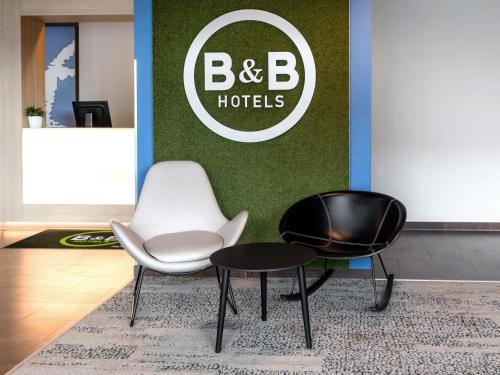 two chairs and a table in a lobby at B&B HOTEL Frankfurt-Hahn Airport in Lautzenhausen