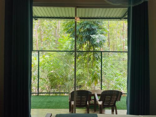 a table and chairs in front of a large window at Forest Edge Safari Villa in Udawalawe