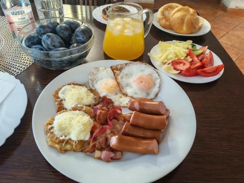 a table with a plate of breakfast food with eggs and bacon at Hársfavirág Vendégház in Pápa