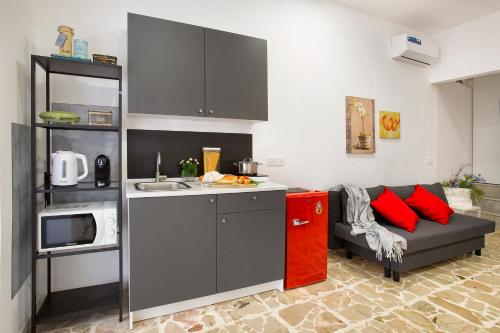 a kitchen with a couch with red pillows in a kitchen at Donna Lucia by Armerina Sicily Apartments in Piazza Armerina