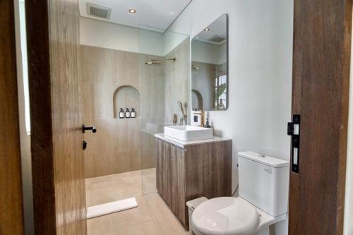 a bathroom with a toilet and a sink and a mirror at Coco Lifestyle Residence in Canggu