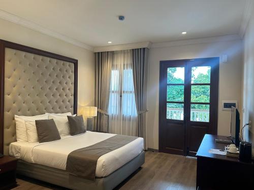a bedroom with a large bed and a window at Champa Palace Hotel in Pakse