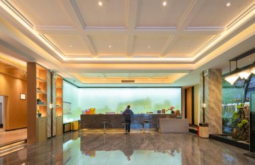 a man standing at a desk in a lobby at GUI YUAN ZHEN PIN HOTEL- Approximately 3 kilometers from the East Gate of Zhangjiajie National Forest Park - Free one-way pick-up or drop-off service for over 3 nights - English speaking customer service in Zhangjiajie