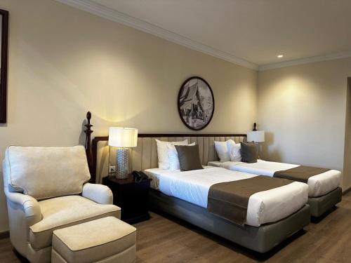 a hotel room with two beds and a chair at Champa Palace Hotel in Pakse