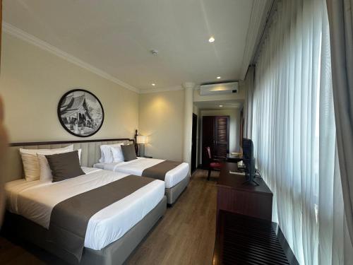 a hotel room with two beds and a television at Champa Palace Hotel in Pakse