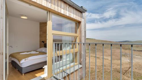 a room with a balcony with a bed and a window at Meadows Terraced Houses in Loučná pod Klínovcem
