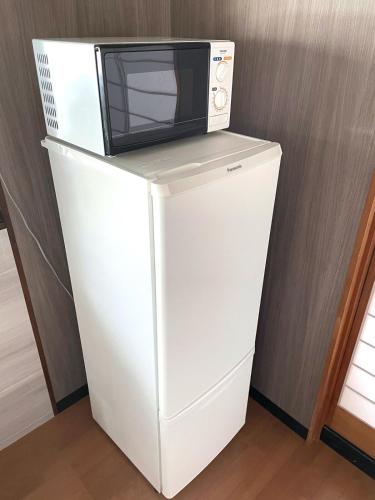 a microwave sitting on top of a white refrigerator at Matsu no Yama, center of Goto, rent the whole house, maximum 7 people in Goto