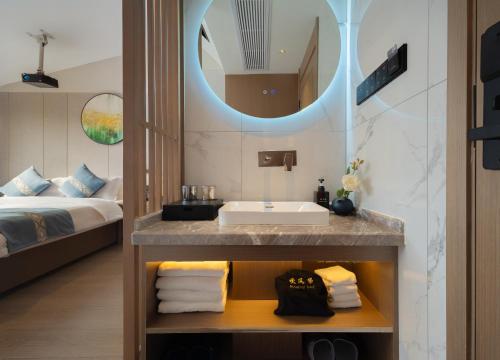 a bathroom with a sink and a bed at GUI YUAN ZHEN PIN HOTEL- Approximately 3 kilometers from the East Gate of Zhangjiajie National Forest Park - Free one-way pick-up or drop-off service for over 3 nights - English speaking customer service in Zhangjiajie