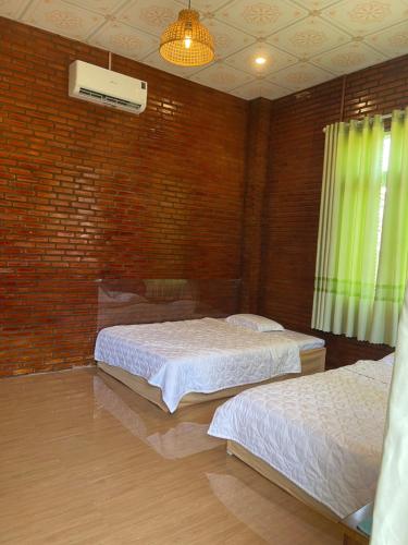 a bedroom with two beds and a brick wall at Sweet Home in Tân Phú