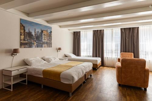 a hotel room with two beds and a chair at Hotel Residence Le Coin in Amsterdam