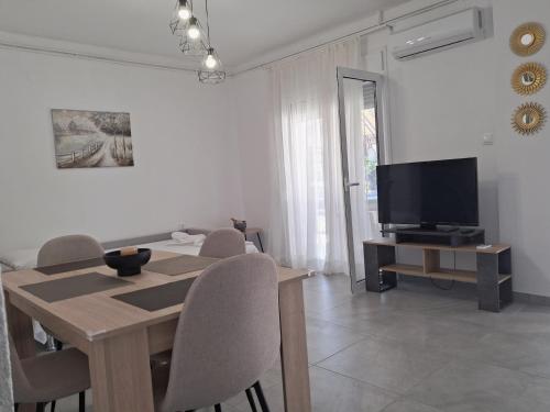 a dining room with a table and a television at SunWaves Apartments in Keramotí