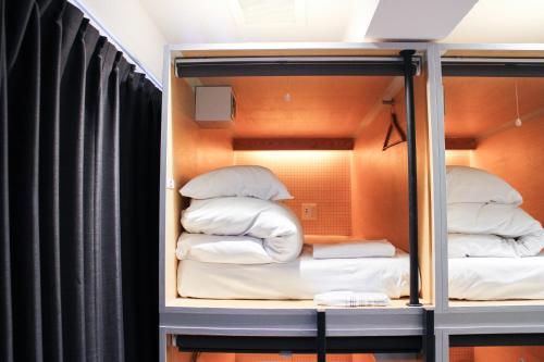 a room with a bunk bed with white pillows at ホステルエリーラ神田 HOSTEL EstLiLas KANDA in Tokyo