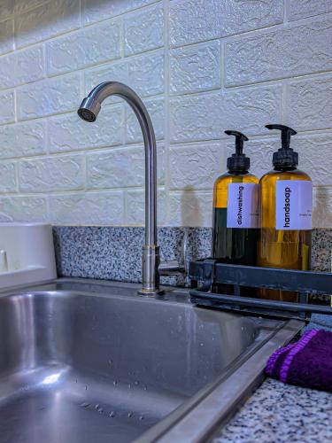 a kitchen sink with two bottles of soap at Condo in Tagaytay - AB Residences in Tagaytay