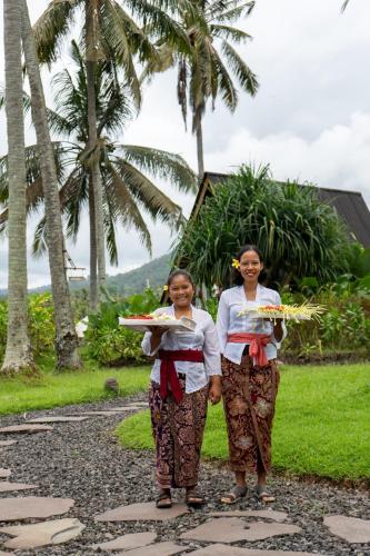 two women standing on a path with plates of food at Desa Cabins in Balian